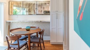 A kitchen with a herringbone tile backsplash, wooden cabinets, and a dining table with chairs.