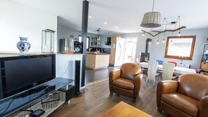 Una sala de estar moderna con televisor de pantalla plana, sillones de cuero y una mesa de centro de madera.