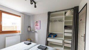 Un dormitorio con dos camas, un armario, una ventana y un cuadro en la pared.