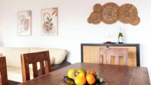 A dining table with fruit, a sofa, and a decorative wall piece.