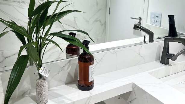 A modern bathroom with a marble backsplash, a large mirror, a sink with a black faucet, and a toilet. - Studio Executivo 230m do metro Brooklin (São Paulo)