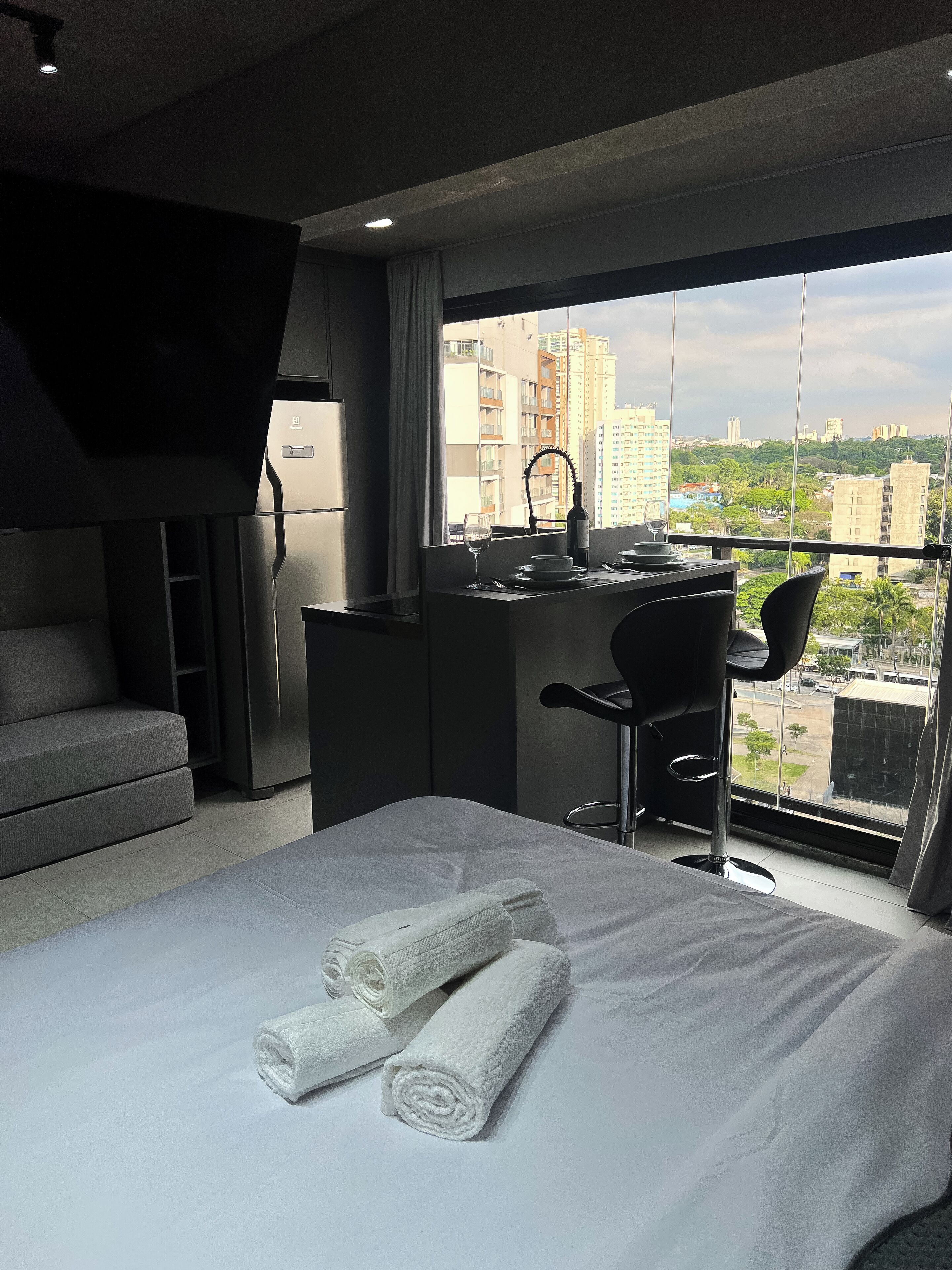 A modern hotel room with a bed, a desk, and a view of the city.