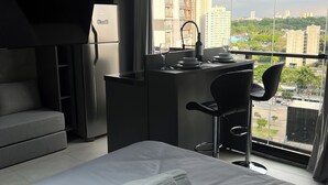 Moderni hotellihuone, jossa on sänky, työpöytä ja näkymä kaupunkiin.