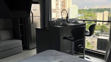 A modern hotel room with a bed, a desk, and a view of the city.