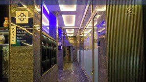 Un couloir d’hôtel avec un sol en marbre, un espace de réception et un panneau indiquant les équipements disponibles, tels qu’une salle de réunion, une salle de sport, un hammam, une piscine et un restaurant.