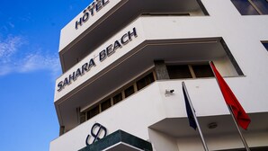 Un hôtel appelé « Sahara Beach », doté d’une architecture moderne, avec une enseigne bien visible et un mât pour drapeau.