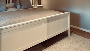 Une chambre à coucher avec un lit, des tables de chevet, une lampe et trois tableaux encadrés accrochés au mur.