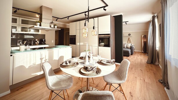 Une cuisine moderne avec des meubles blancs, un îlot central et des luminaires suspendus.