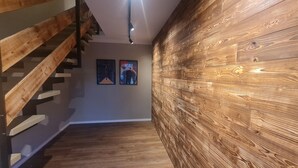 Un escalier en bois au design moderne, un panneau mural en bois et deux œuvres d’art encadrées accrochées au mur.