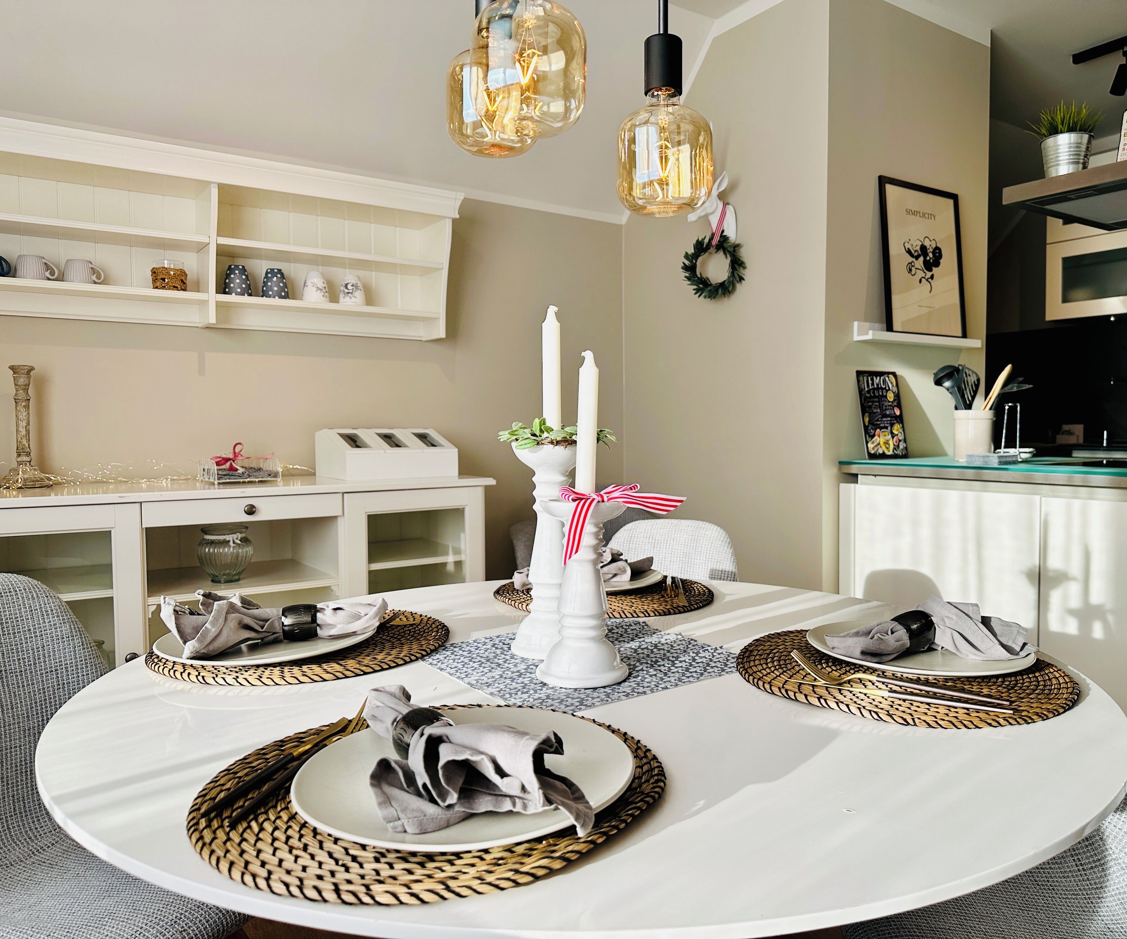 A dining area with a round table set for four, featuring woven placemats and white plates.