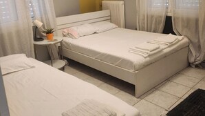 A hotel room with two beds, a bedside table with a lamp, a radiator, and sheer curtains. - jim vila (Andravida)