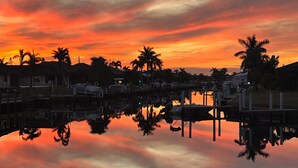A marina at sunset with boats docked, palm trees, and houses along the waterfront. - Be one of the first guests to enjoy this newly renovated luxury waterfront villa (Punta Gorda)