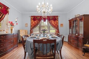A dining room with a chandelier, red curtains, and a wooden cabinet.