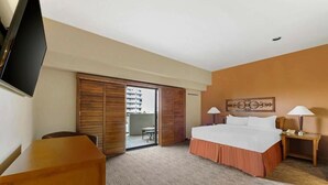 Habitación de hotel con cama, escritorio, televisor, armario y vistas al exterior.