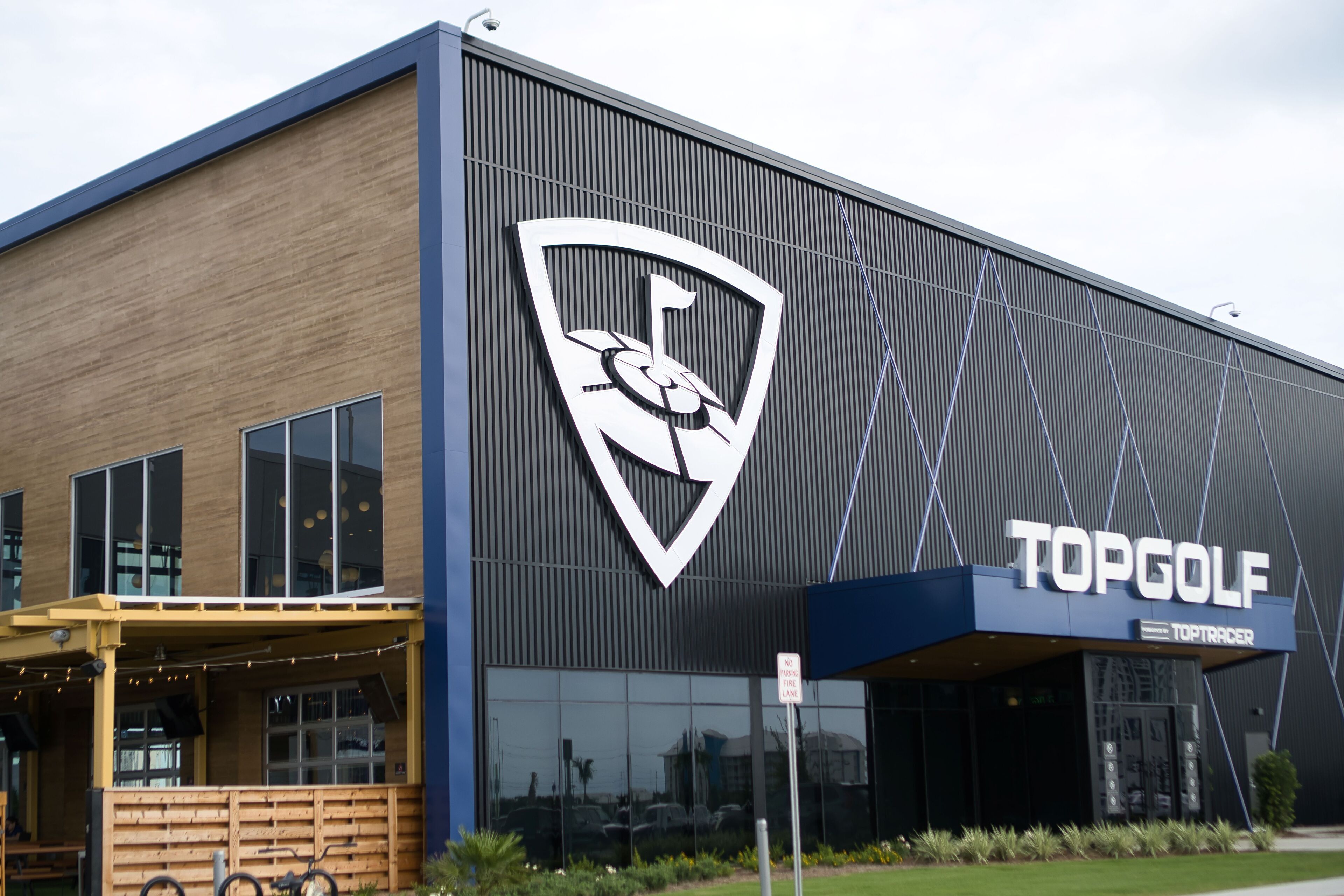 En modern byggnad med en stor logotyp och namnet ”TOPGOLF” på fasaden.
