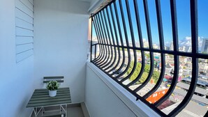 Un balcón con vista a la ciudad, una mesita con una planta y una silla.