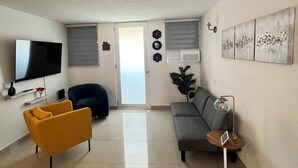 Una sala moderna con una televisión de pantalla plana, un sofá, un sillón amarillo y una mesa de centro.