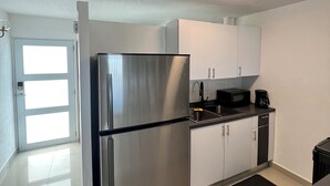 Una cocina moderna con electrodomésticos de acero inoxidable, armarios blancos y encimera negra.