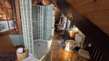 Experience a bathing experience in this bathroom with a glass-enclosed shower and a small sink and toilet area.