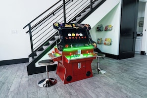 A space-themed arcade game machine in a room with a staircase and a bookshelf.