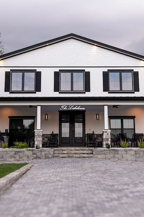 A two-story building with a white facade, black shutters, and a sign reading 'The Lakehouse.'