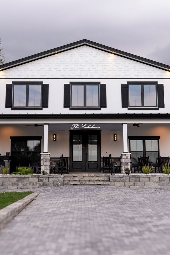 A two-story building with a white facade, black shutters, and a sign reading 'The Lakehouse.'