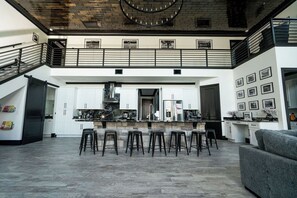 A modern kitchen with a central island, bar stools, and a staircase leading to an upper level.