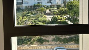 A modern building with a flat roof and white exterior walls, surrounded by a well-maintained garden with various plants and a paved pathway. - Cosy and chic one-bedroom apt with 3 beds - Taghazout Bay (Sidi Bouzid)
