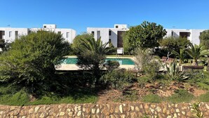 A modern building complex with a pool surrounded by greenery and a stone wall. - Cosy and chic one-bedroom apt with 3 beds - Taghazout Bay (Sidi Bouzid)