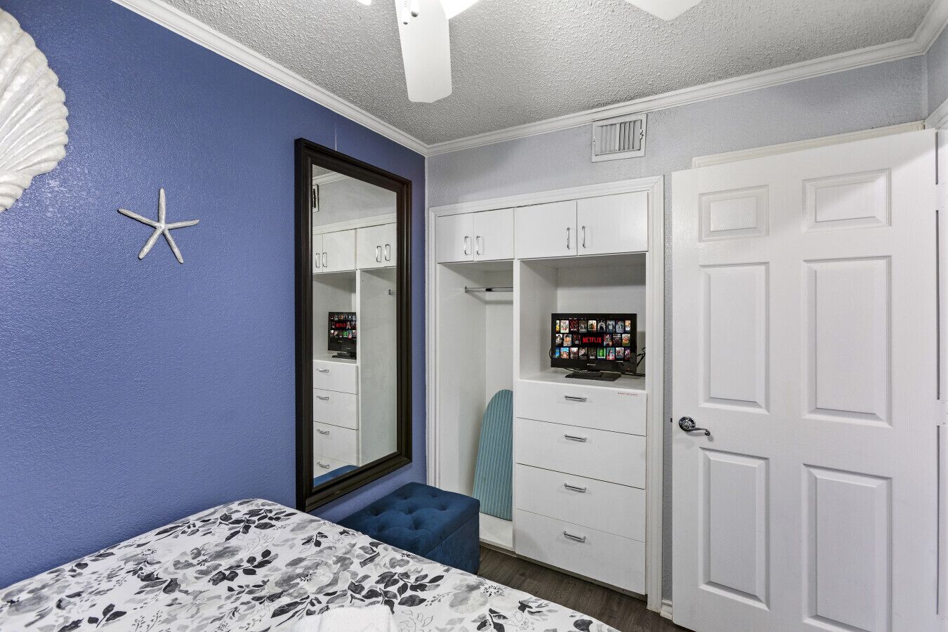 A bedroom with a bed, a wardrobe, a mirror, and a TV on a cabinet.