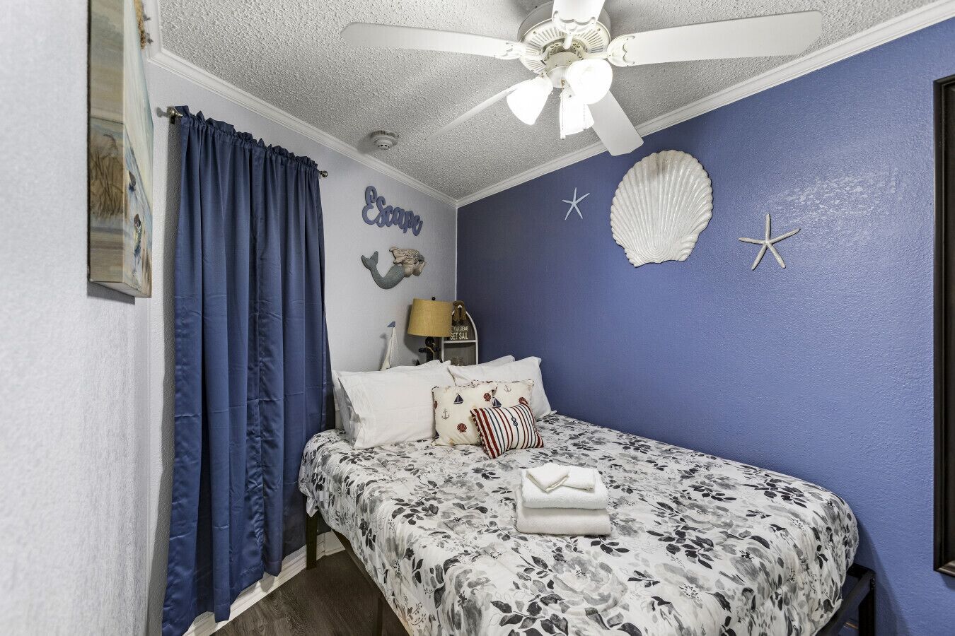 Un dormitorio con una cama, ventilador de techo, lámpara y adornos en la pared.