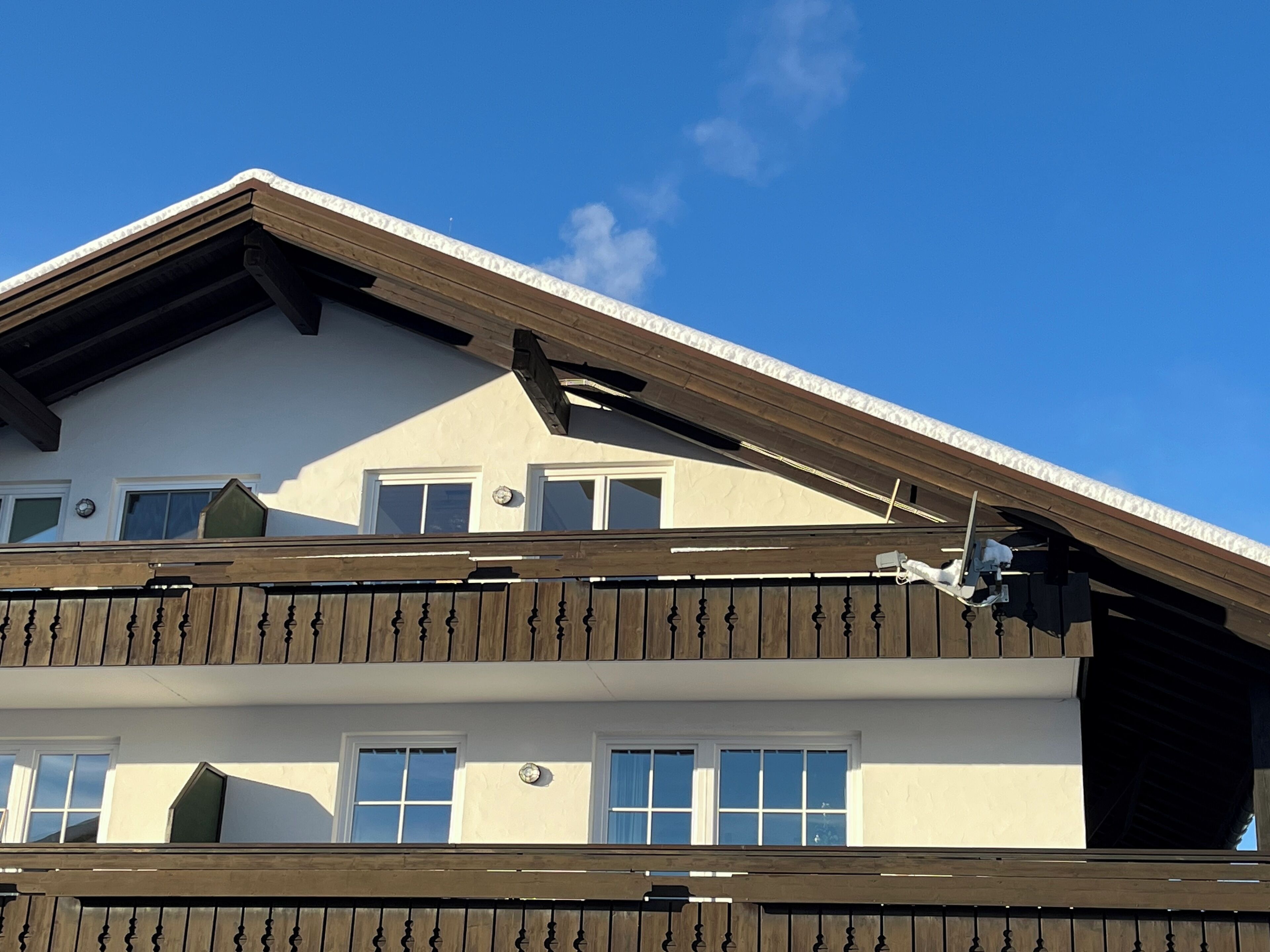 A multi-story building with a sloped roof, wooden balcony railings, and multiple windows.