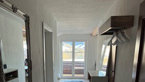 Ett rymligt rum med en stor skjutdörr i glas som leder ut till en balkong, en vit garderob och en liten sittgrupp.
