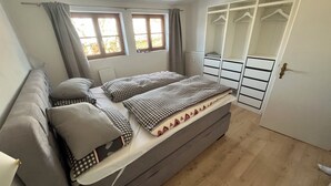 Ett sovrum med en säng, en soffa, en garderob och ett fönster.