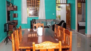 Un comedor con una mesa y sillas de madera, un sofá y un ventanal con cortinas.