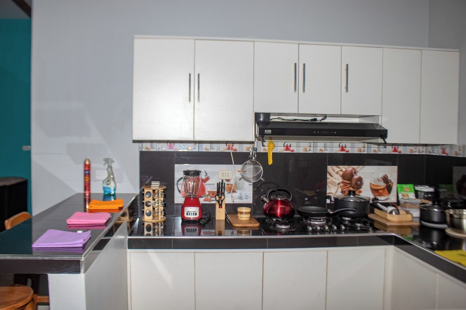 Een moderne keuken met witte kasten, een zwart aanrecht en diverse keukenapparaten.