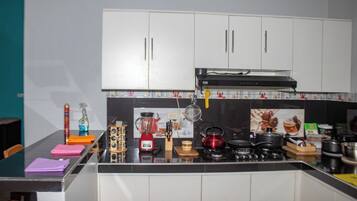Een moderne keuken met witte kasten, een zwart aanrecht en diverse keukenapparaten.