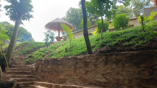 Un conjunto de escalones de piedra que conducen a una colina, con una construcción de techo de paja al fondo.