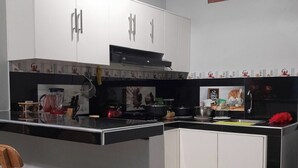 Una cocina con armarios blancos, encimera negra y una ventana con persianas.