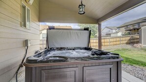 A hot tub with a wooden exterior, a white cover, and a hanging lantern. - Front Range Getaway - 4 beds with Jacuzzi (Colorado Springs)
