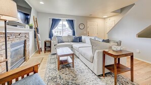 A modern living room with a sectional sofa, a fireplace, and a staircase. - Front Range Getaway - 4 beds with Jacuzzi (Colorado Springs)