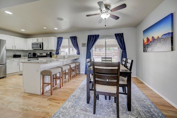 A modern kitchen with white cabinets, a microwave, and a dining area with a table and chairs.