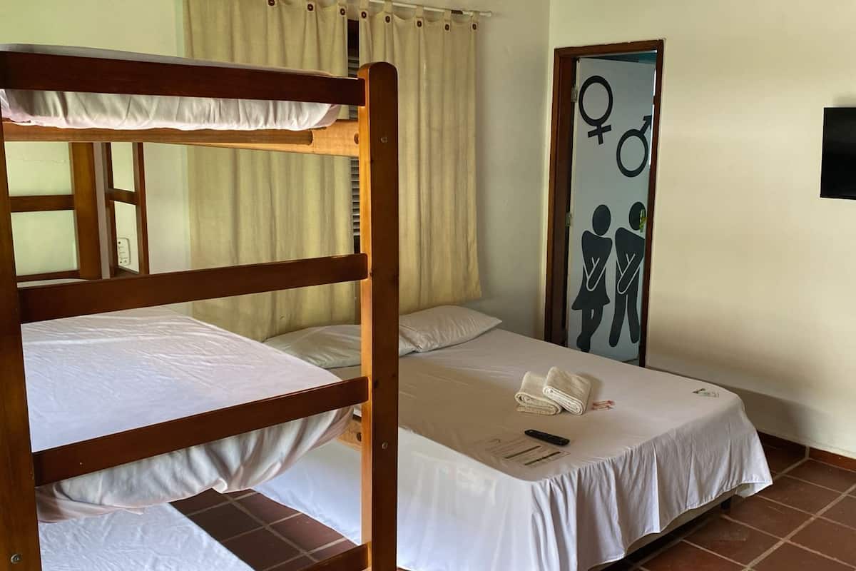 Une chambre avec un lit superposé, un lit simple, un téléviseur fixé au mur et une œuvre d’art représentant un symbole de genre.