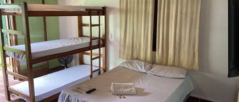Una habitación con una litera, una cama individual, un ventilador y un televisor.