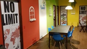 A room with a wooden table and blue chairs, a 'NO LIMIT' sign, and a world map. - 4 Elements Inn Guarujá (Guarujá)