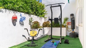 Ein kleiner Trainingsbereich im Freien mit Klimmzugstange, Bank, Yogamatte und Sandsack.