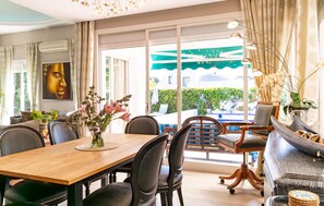 A dining area with a wooden table, black upholstered chairs, and a view of a swimming pool through large glass doors. - Nice home in Marbella (Marbella)