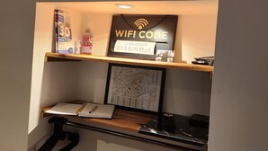 A desk with a lion head decoration, a framed map, a laptop, a notebook, and a shelf with a WiFi code sign. - The wash house (Ballan-Miré)