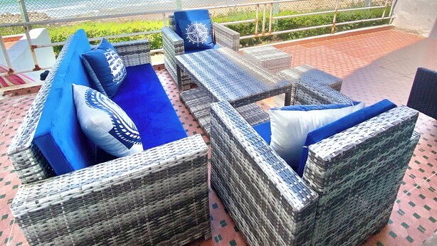 A balcony with wicker furniture and a view of the beach.