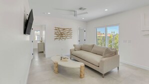 Un salon moderne avec un canapé, une table basse et un téléviseur fixé au mur.